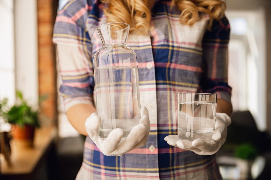 close-up-female-hands-gloves-holding-bottle-glass-with-pure-water.jpg